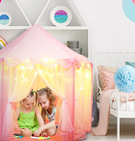 Two little girls playing inside the Orian pink castle tent in a bedroom